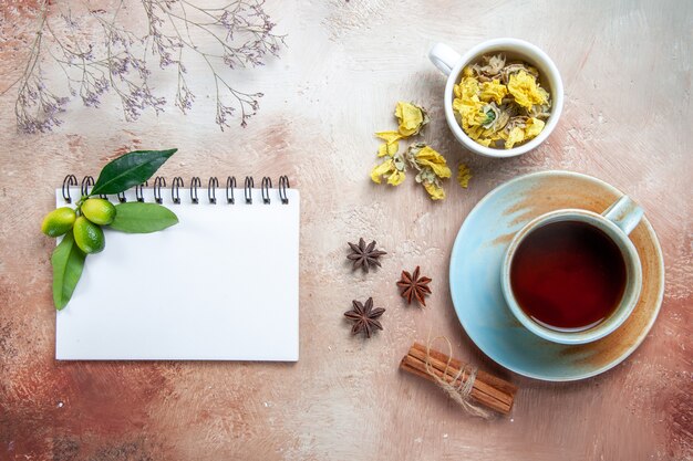 Vista superior de primer plano una taza de té una taza de té canela en rama cuaderno de hierbas