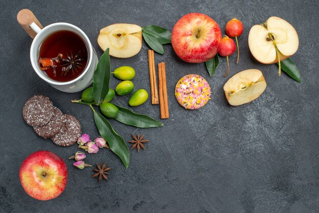 Vista superior de primer plano una taza de té una taza de té de hierbas palitos de canela manzanas galletas cítricos