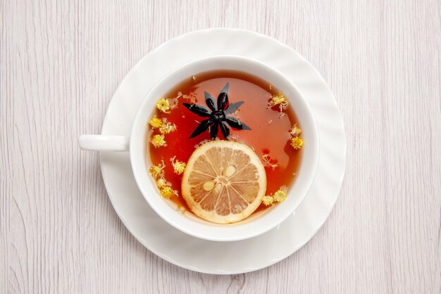Vista superior de primer plano una taza de té una taza de té con una rodaja de limón en el platillo blanco en la mesa de madera blanca