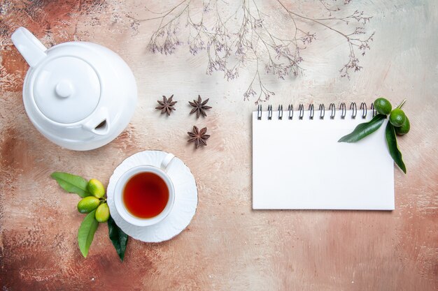 Vista superior de primer plano una taza de té una taza de té tetera blanca frutas cítricas anís estrellado cuaderno