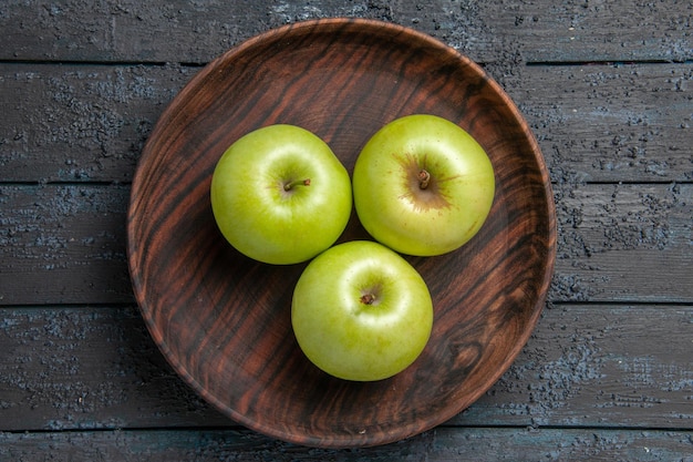 Foto gratuita vista superior de primer plano tazón de fuente de madera de manzanas de apetitosas manzanas verdes sobre superficie oscura