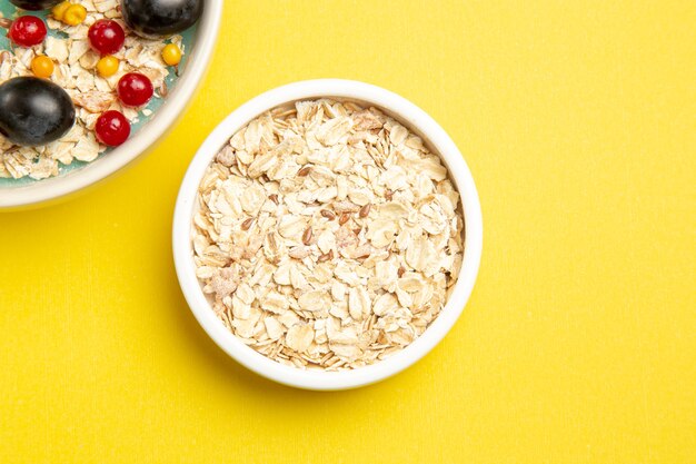 Vista superior de primer plano tazones de bayas de la apetitosa avena en la mesa amarilla