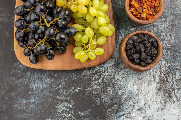 Vista superior de primer plano uvas frutos secos la tabla de cortar con racimos de uvas sabrosas