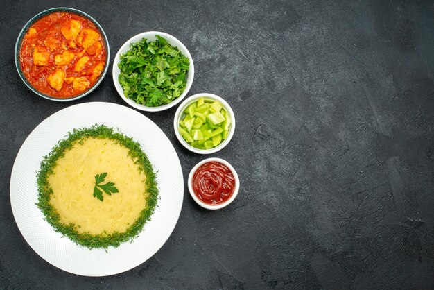 Vista superior de puré de patatas con verduras y salsa de tomate en gris