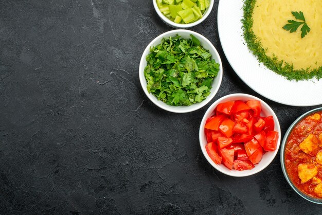 Vista superior de puré de patatas con verduras y tomates en rodajas en gris