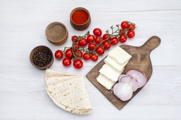 Vista superior de queso blanco junto con tomates rojos frescos cebollas en el escritorio blanco comida vegetal almuerzo