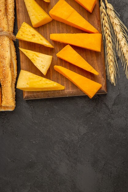 Vista superior de queso fresco en rodajas con bollos sobre el fondo oscuro