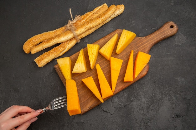 Foto gratuita vista superior de queso fresco en rodajas con bollos sobre el fondo oscuro