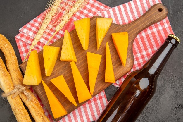 Foto gratuita vista superior de queso fresco en rodajas con botella sobre fondo gris oscuro