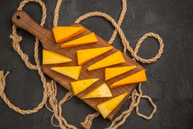 Foto gratuita vista superior de queso fresco en rodajas con cuerdas sobre fondo oscuro