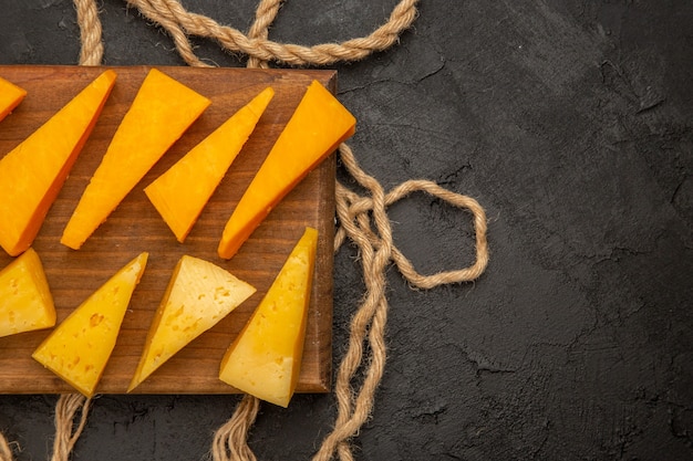 Vista superior de queso fresco en rodajas con cuerdas sobre fondo oscuro