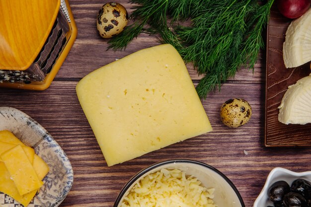 Vista superior de queso holandés con huevos de codorniz eneldo y queso rallado en un recipiente sobre madera rústica