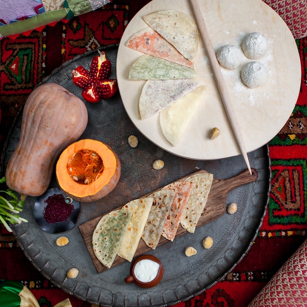 Foto gratuita vista superior qutab surtido con calabaza y granate y tabla de masa en tabla de cortar