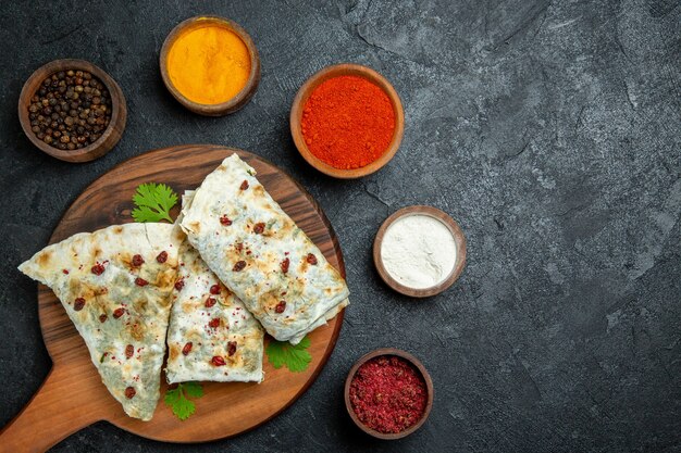 Vista superior de qutabs deliciosos con diferentes condimentos en la comida del piso gris para cocinar masa, carne, aceite, comida
