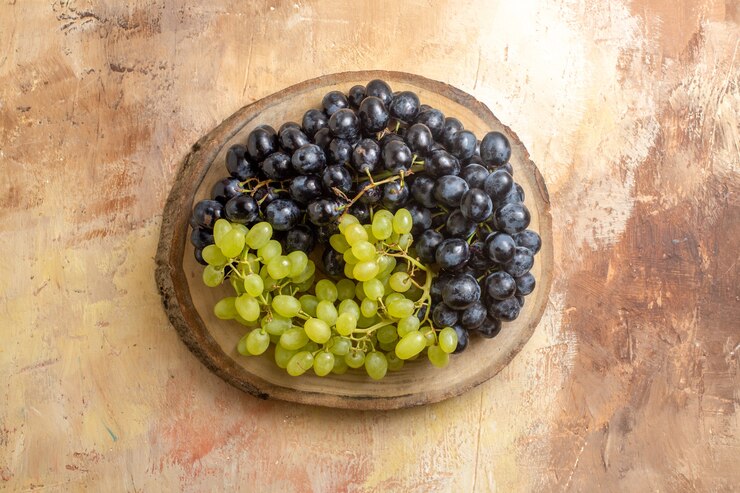 Foto gratuito vista superior de racimos de uvas de uvas verdes y negras en el tablero de la cocina