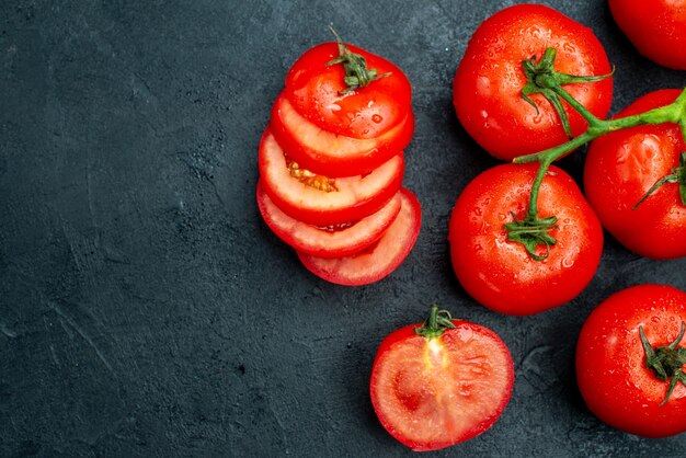 Vista superior de la rama de tomate rojo fresco tomates rojos picados en mesa negra con lugar de copia