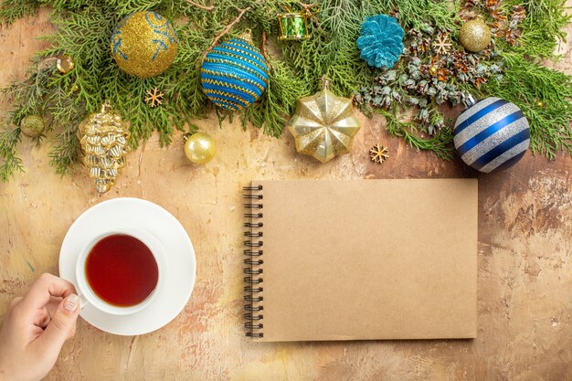 Vista superior de ramas de abeto adornos de árbol de Navidad una taza de té portátil sobre fondo beige