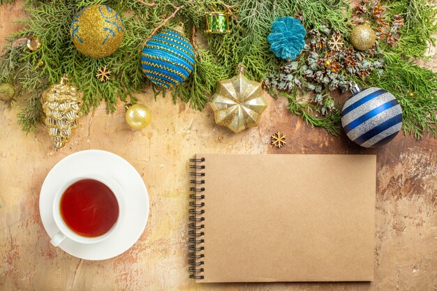 Vista superior de ramas de abeto adornos de árbol de Navidad una taza de té portátil sobre fondo beige