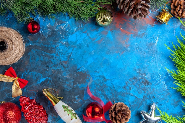 Vista superior de las ramas de los árboles de pino con piñas de hilo de paja adornos colgantes de Navidad en la superficie azul-roja