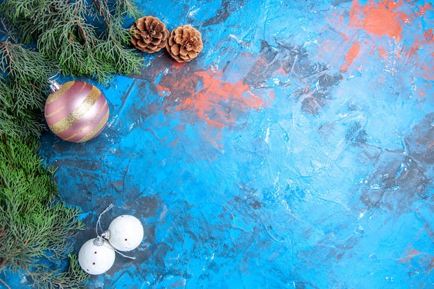 Vista superior de ramas de pino piñas bolas de árbol de Navidad en superficie azul-roja