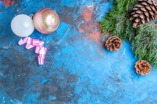 Vista superior de ramas de pino piñas bolas de árbol de Navidad en superficie azul-roja