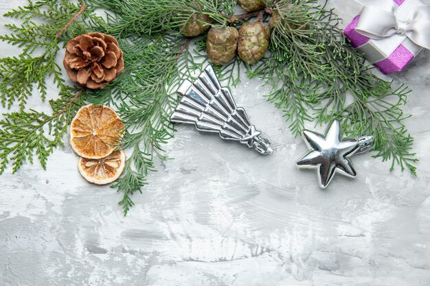 Vista superior ramas de pino rodajas de limón piñas pequeño regalo juguetes de árbol de Navidad sobre fondo gris