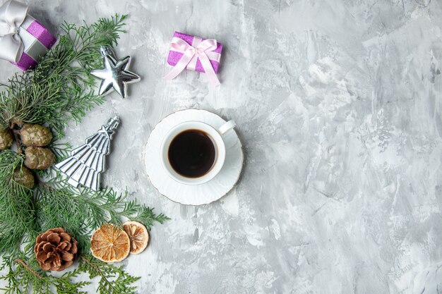 Vista superior ramas de pino taza de té rodajas de limón seco piñas pequeños regalos en superficie gris