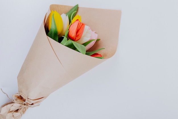 Foto gratuita vista superior de un ramo de coloridas flores de tulipán en un papel artesanal sobre fondo blanco con espacio de copia