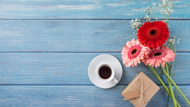 Vista superior del ramo de flores con caja de regalo y taza de café