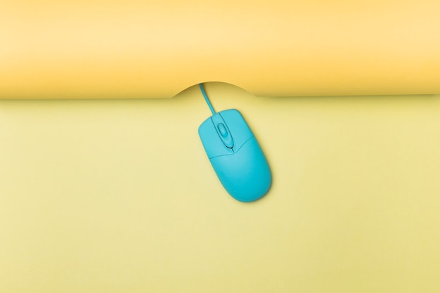 Vista superior del ratón de la computadora azul con fondo amarillo