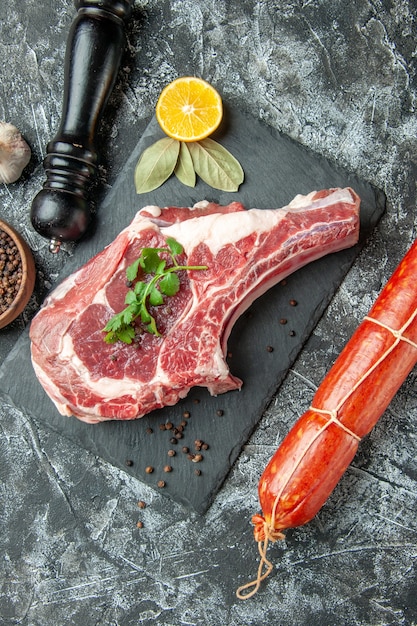 Vista superior de la rebanada de carne fresca con salchicha sobre fondo gris claro cocina animal vaca carne de pollo color de alimentos carnicero