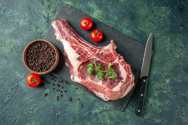 Vista superior de la rebanada de carne fresca con tomates y pimiento sobre un fondo azul oscuro carne de carnicero de color de comida de pollo de vaca animal de cocina