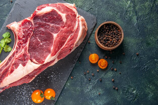 Vista superior rebanada de carne grande carne cruda con pimienta sobre superficie oscura