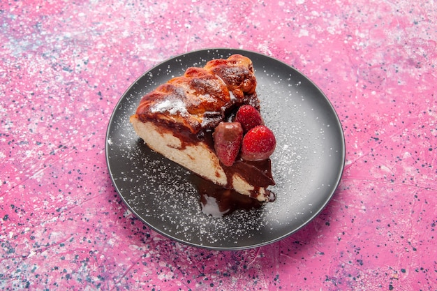 Vista superior de la rebanada de pastel con chocolate y fresas rojas sobre pastel de postre de azúcar dulce de galleta de escritorio rosa