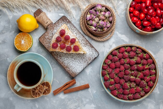 Vista superior rebanada de pastel delicioso con taza de té frambuesas cornejos en la mesa de luz pastel galleta dulce azúcar hornear