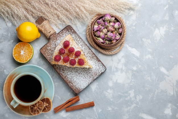 Vista superior rebanada de pastel delicioso con taza de té y limones en la mesa de luz pastel galleta dulce azúcar hornear