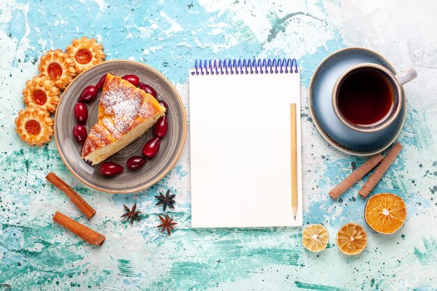 Foto gratuita vista superior rebanada de pastel delicioso con taza de té en la superficie azul claro pastel hornear pastel galleta dulce