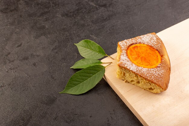 Una vista superior rebanada de pastel de naranja dulce delicioso sabroso en el escritorio de madera de color crema y fondo gris galleta de azúcar dulce