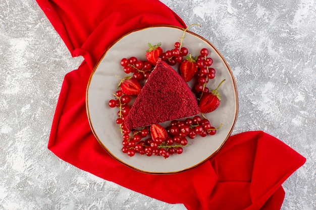 Vista superior rebanada de pastel rojo pedazo de pastel de frutas dentro de la placa con arándanos frescos y fresas en el escritorio gris pastel de té de galletas dulces