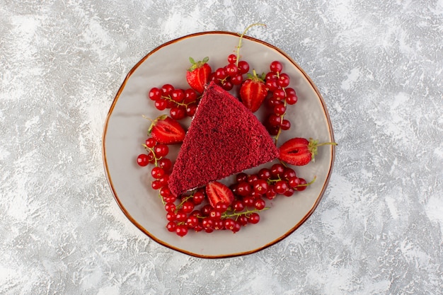 Vista superior rebanada de pastel rojo pedazo de pastel de frutas dentro de la placa con arándanos frescos sobre el fondo gris pastel de té de galletas dulces