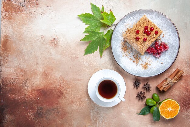 Foto gratuita vista superior de la rebanada de pastel con té y frutos rojos en piso ligero pastel galleta dulce