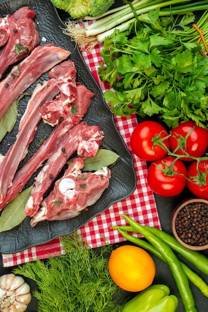 Vista superior rebanadas de carne cruda con condimentos verdes y tomates rojos sobre fondo oscuro plato carne ensalada comida cocina carnicero comida