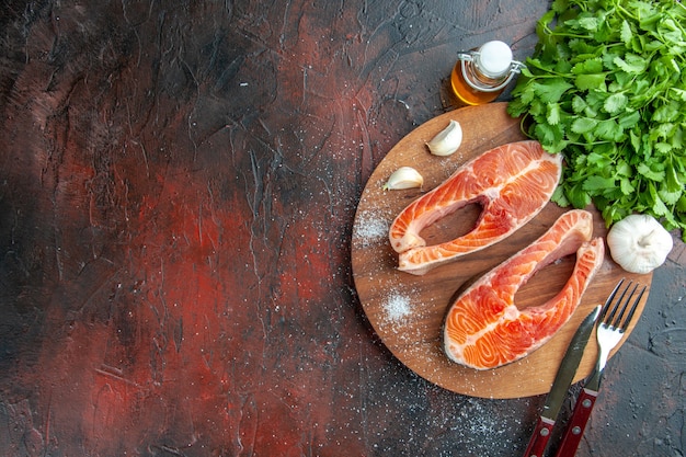 Vista superior de las rebanadas de carne cruda con verduras sobre un fondo oscuro