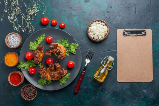 Vista superior de las rebanadas de carne frita con aceite de oliva y condimentos en un escritorio azul oscuro, verduras, carne, comida saludable