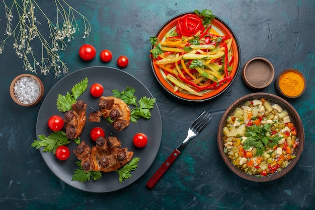 Vista superior de las rebanadas de carne frita con sopa de verduras y condimentos en el escritorio azul oscuro comida vegetal comida carne cena