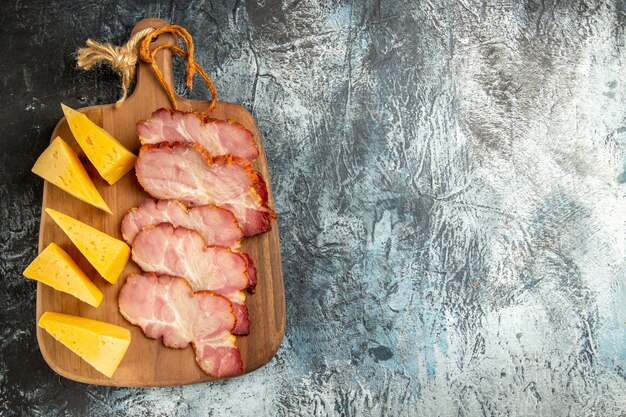 Vista superior rebanadas de carne rebanadas de queso en tabla de cortar sobre fondo gris