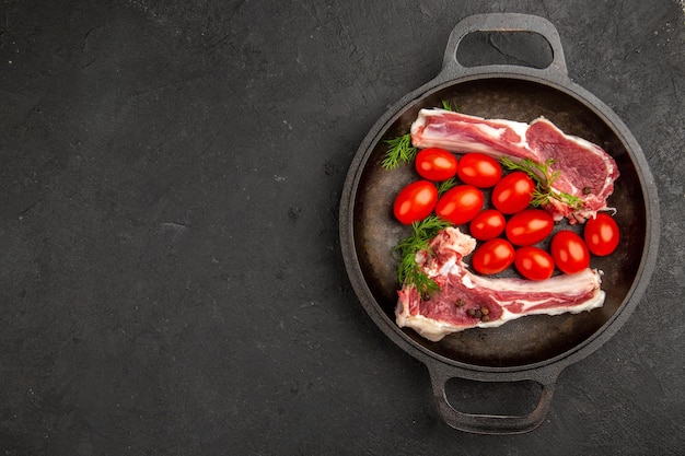 Vista superior rebanadas de carne con tomates rojos dentro de la sartén sobre fondo gris pollo vaca cruda pimienta color carne foto animales