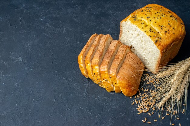 Vista superior de rebanadas de pan, espigas de trigo y granos en una mesa oscura con espacio libre