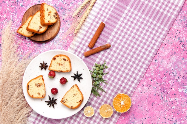 Foto gratuita vista superior de las rebanadas de pastel con fresas y canela en el fondo rosa pastel hornear galletas dulces tarta de color galletas de azúcar