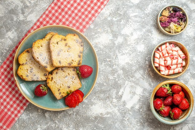 Vista superior de rebanadas de pastel con fresas frescas y dulces en frutas de pastel de superficie ligera